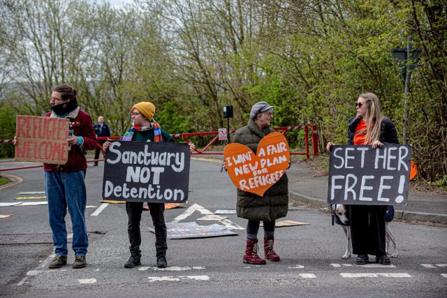 Standing united at Hassockfield: Demonstrators line the road, some with flares and others holding signs, calling for urgent reforms in immigration detention practices. Their powerful display underscores a community's demand for humane treatment and policy change.