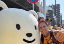 Tokyo Marathon Success for Street Child Fundraiser Natasha Pollock in Street Child vest posing with a mascot during the Tokyo Marathon