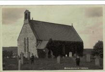 What a Postcard Revealed: the Story of Joseph Thompson Maddison A 1913 black and white postcard photograph of Muggleswick Church, a small stone church with a bellcote and ivy-covered wall, with two men in flat caps standing among the gravestones