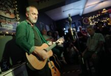 The only independent venue in Stanley A performer playing acoustic guitar and singing to an audience at The White Room in Stanley.