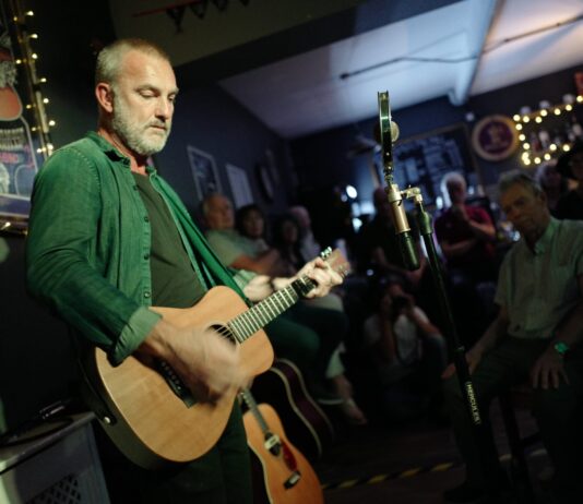 The only independent venue in Stanley A performer playing acoustic guitar and singing to an audience at The White Room in Stanley.