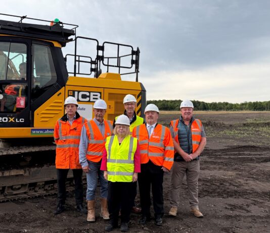 Ground broken in Consett for new hospital A group in hard hats and high visibility jackets standing on the cleared site of the new Shotley Bridge Hospital, beside an excavator.